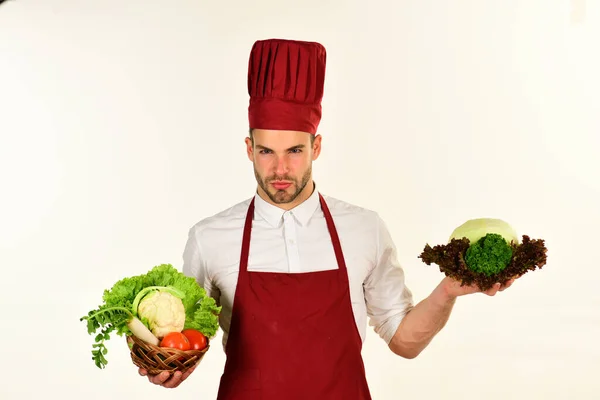 Essenszubereitung. Chef mit strenger Miene hält Salat und Kohl — Stockfoto