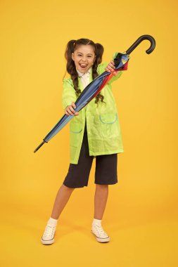 Korunmuş ve mutlu hissediyorum. Sonbahar sezonu için aksesuar. Sonbahar çocuk modası. Yağmurlu havada kuru ve rahat. Şemsiyeli küçük bir kız. Öğrenci kız su geçirmez yağmurluk. Keyfi yerinde.