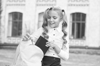 Edebiyat ödevi. Okul çantasından kitap seçen mutlu çocuk. İngiliz edebiyatı ve şiir kitabı. Edebiyat eğitimi. Okul kütüphanesi. Eğitim ve eğitim. Açık havada edebiyat ustası