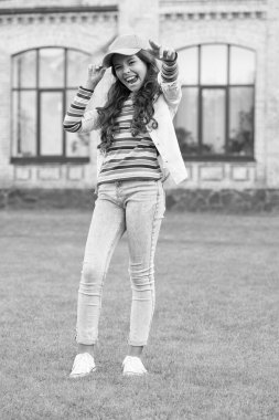 Yürüyen yeşil çimenler. Etrafta dolaşırdı. Liseli kız şapka takıyor. Gündelik tarz ve şapkalı bir genç. Çocuk dışarıda gülümsüyor. Güzellik ve moda. Çocukluk mutluluğu. Kıvırcık saçlı, şapkalı mutlu kız.