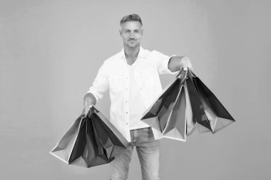 Alışveriş yap ve keyfine bak. Mutlu alışveriş yapan mavi arka plan. Yakışıklı adam alışveriş torbalarını tutuyor. Hediyelik eşya dükkanı. Tatil hazırlığı. Hediyelik eşya dükkanı. İndirim ve indirim. Düşene kadar alışveriş yap.