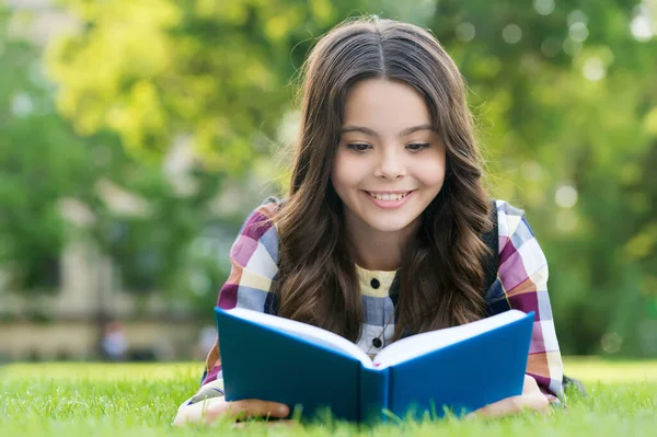 Ler só aumenta o seu conhecimento. Criança feliz ler livro deitado na grama verde. Biblioteca da escola. Imaginação e fantasia. Educação de alfabetização. Ler é um bom hobby — Fotografia de Stock