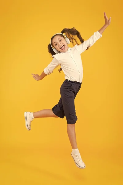 Aula de dança. Pequena dançarina movendo-se para a música em fundo amarelo. Criança gosta de dançar com música moderna. Criança energética a dançar com prazer. Aprendendo na escola de dança — Fotografia de Stock