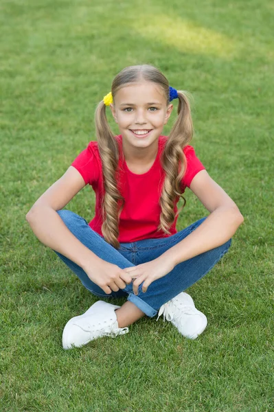 Menina bonito rabo de cavalo penteado relaxante na grama verde, conceito de férias de verão — Fotografia de Stock