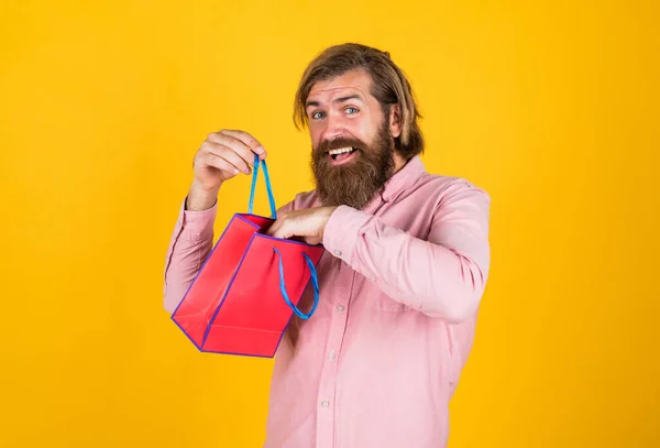 buy anniversary gifts. surprised male open shopping bag with something exciting inside. mature man looking casual in surprise with present package. commonly used for birthday. Shopping time