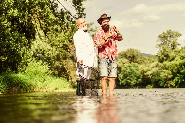 Aproveitando dia de pesca. pai aposentado e filho barbudo maduro. amigos homens com vara de pesca e rede. passatempo de homem de negócios. pesca da reforma. pescadores felizes. Bom lucro. Aventuras de pesca com mosca — Fotografia de Stock