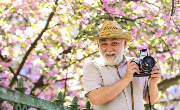 Spring holidays. Travel photo. Retirement travel. Capturing beauty. Photographer in blooming garden. Senior man hold professional camera. Photography courses. Happy grandfather. Travel and tourism — Stock Photo, Image