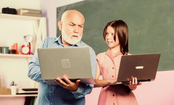 Ayudarte a estudiar. nuevas tecnologías en el aprendizaje. lección de la escuela en línea. Buscador. niña pequeña con hombre tutor estudio en la computadora. blogueo educativo. De vuelta a la escuela. maestro maduro ayuda alumna —  Fotos de Stock