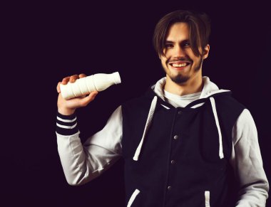 Siyah stüdyo arka planında beyzbol ceketli gülen adam.