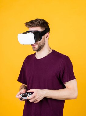 Modern teknolojiler. Adam kablosuz internet gözlüğü takıyor. Adam video oyunu oynuyor. Konsollu oyun oyuncusu. VR kulaklıklı bir erkek. Mutlu oyuncular modern teknolojiyi kullanır. Dijital gelecek ve yenilik. Görsel gerçeklik