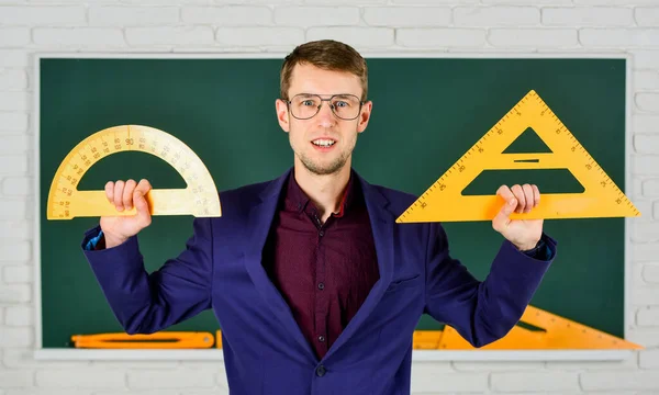 Disciplinas de la escuela madre. concepto de matemáticas y personas. Hombre en pizarra. de vuelta a la escuela. geometría tema favorito. Profesor masculino sostenga transportador y triángulo. educación en la escuela — Foto de Stock