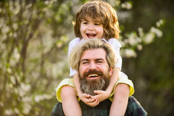 Başarıyı kutluyoruz. Parkta çiçek açan ağaç. çocukluk ve ebeveynlik mutluluğu. Sevgi ve destek. Baba ve oğul çiçek açan ağaçta. Bahar zamanı birlikte. Küçük çocuk babasıyla mutlu. Aile eğleniyor.