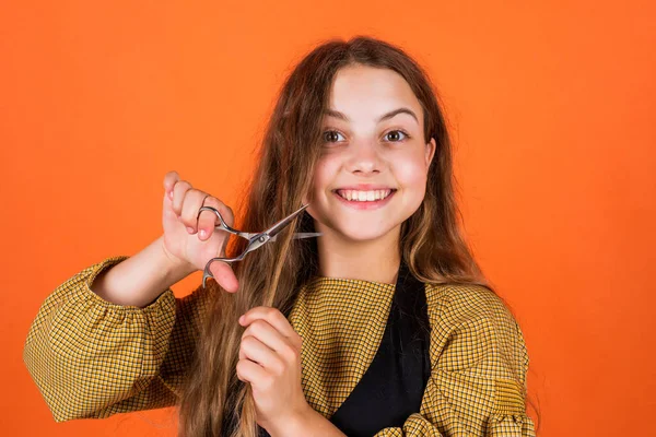 Teenie-Mädchen schnitt sich die Haare mit der Schere. machen neue Frisur. Kinder benutzen Scherenwerkzeug im Schönheitssalon. Mode der Frisur. Kind schneiden lange brünette Haare. Haarpflege und Gesundheit. Friseur. Alltagskleidung — Stockfoto