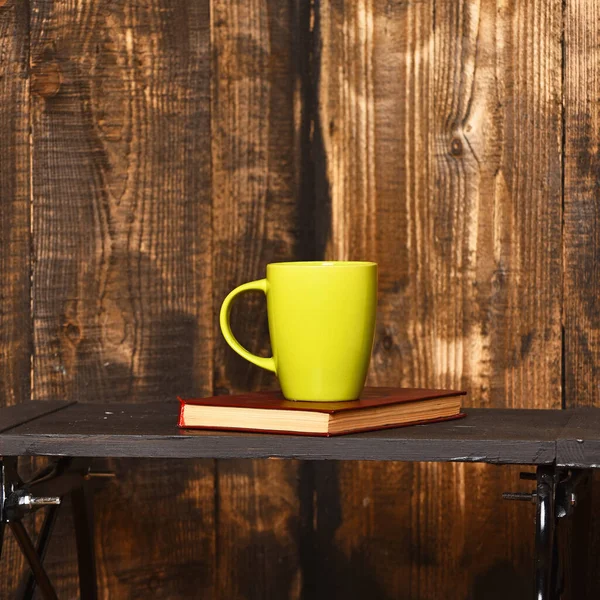 Green cup and notebook on small black table. — Stock Photo, Image