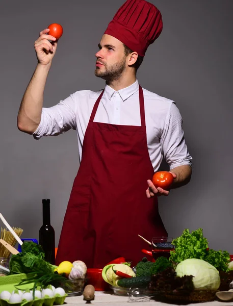 Man med skägg håller tomater på grå bakgrund. — Stockfoto