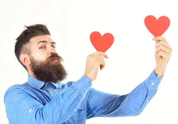Hipster usa camisa de mezclilla. Feliz hombre barbudo sostiene corazones rojos —  Fotos de Stock