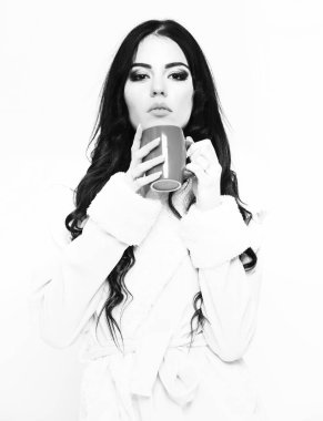 Bej renkli kadife bornoz giyen seksi kız elinde bardak tutuyor.