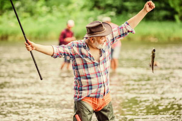 Take that best. sport activity and hobby. Trout bait. retired bearded fisher. big game fishing. summer weekend. fisherman with fishing rod. pothunter. man catching fish. mature man fishing