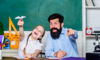Sakallı pedagog ve öğrenci eğleniyor. Etkin bir şekilde büyüyen ve gelişen ilgili öğrenciler. Okul boş zamanlarında öğreniyor. Öğrencilerden oluşan bir topluluk yaratmak. Öğretmen ve okul kızı.