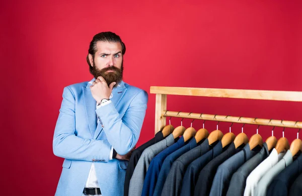 Large selection of mens suits. bearded man choose jacket on hanger. male wardrobe concept. man go shopping in clothing store. our studio atelier presents any fashion style — Stock Photo, Image