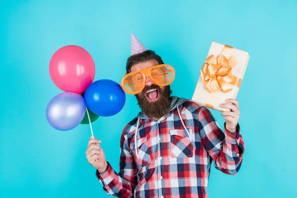 Einkaufen gehen. Hipster lächelnd mit Luftballon. Feiern fröhliche Party. Party-Elemente und Ferienobjekte. Bunten Spaß. beste Party für den Ruhestand. Fröhlicher Mann mit Bart hält Geschenk in der Hand — Stockfoto