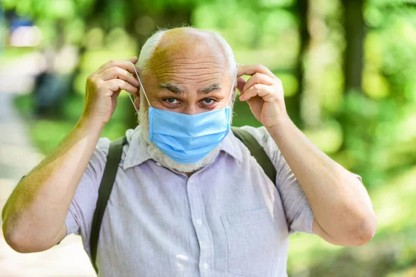 Een warme dag. park is gesloten voor quarantaine vanwege coronavirus. senior man met masker. genieten van de lente natuur boom buiten. coronavirus covid19. Lentegenot. beperkt openbaar park — Stockfoto