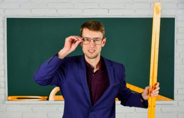 Elinde cetvel olan öğretmen okula geri döndü.