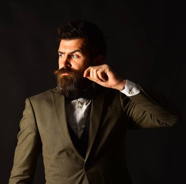 Klasik takım elbiseli yakışıklı genç adam bıyığını kıvırıyor.