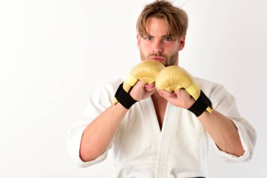 Adam altın boks eldiveni giymiş beyaz kimonoyla poz veriyor.