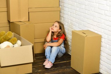 Çocuk köşedeki tahta zeminde oturuyor.