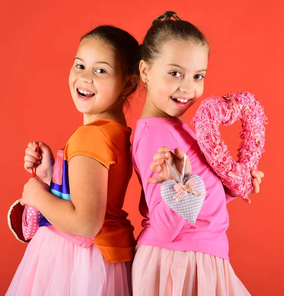 Gülen yüzlü çocuklar kırmızıda sırt sırta dururlar.