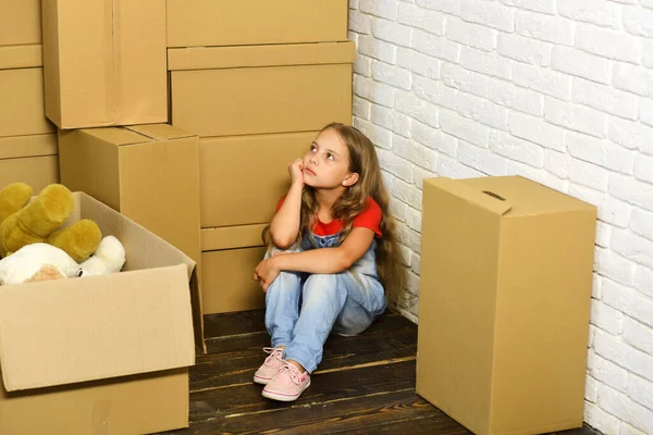 Çocuk köşedeki tahta zeminde oturuyor.