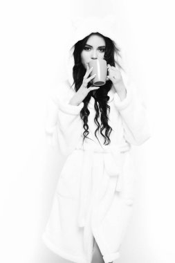 Fincanlı bej kadife bornozla poz veren seksi kız.