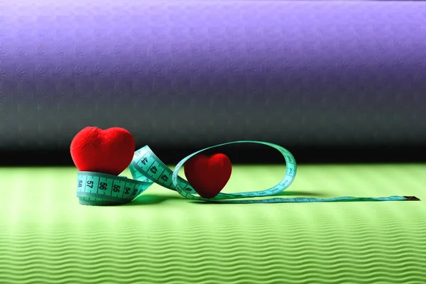 Decorações de coração e régua flexível deitado no tapete de ioga. — Fotografia de Stock