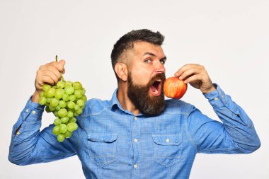 Aç suratlı şarap üreticisi üzüm ve meyve tutuyor..