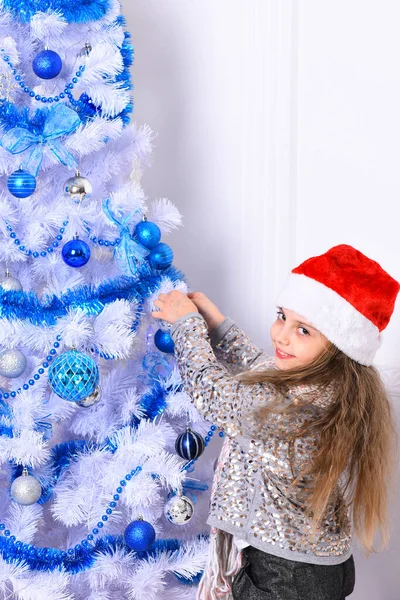 Міс Санта у капелюсі прикрашає біло-синю ялинку. — стокове фото