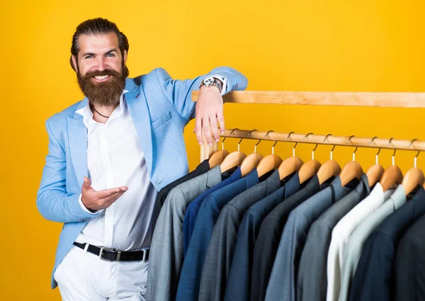 Stylish mens clothing on hanger stand in room. business fashion style. dry cleaning service. style and people concept. Handsome man in smart casual wear looking at suits and choosing. Cool and sexy — Stock Photo, Image