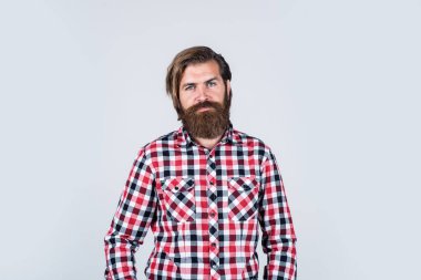 Moda bir görünüm. Bıyıklı, vahşi beyaz adam. Sakallı adam kareli gömlek giyer. Kendine güvenen ve yakışıklı vahşi bir adam. Erkek berber bakımı. Saç ve sakal bakımı. Sakallı olgun hippi.