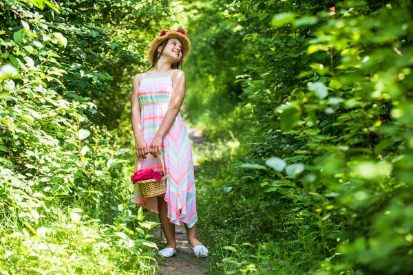 Inizio della vita. Bella ragazza in cappello di paglia raccogliere rose. infanzia felice. bella ragazza con i fiori. bambina che tiene rosa fresco bouquet di fiori fioriti di rose. composizione dei fiori — Foto Stock