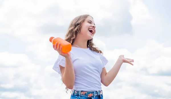 Drinking natural juice in summer. portrait of pretty child girl. happy childhood. cheerful teen girl has long curly hair. kid outdoor with bottle of water. kid fashion and beauty — Stock Photo, Image