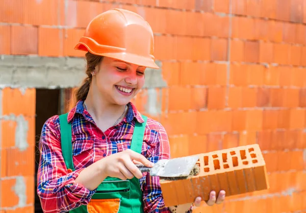 Processo fascinante. A criança é arquitecta engenheira. a construir a sua futura casa. infância feliz. O miúdo usa capacete protector. proteger a cabeça no canteiro de obras. Menina segurar tijolo. pequeno construtor com tijolo — Fotografia de Stock