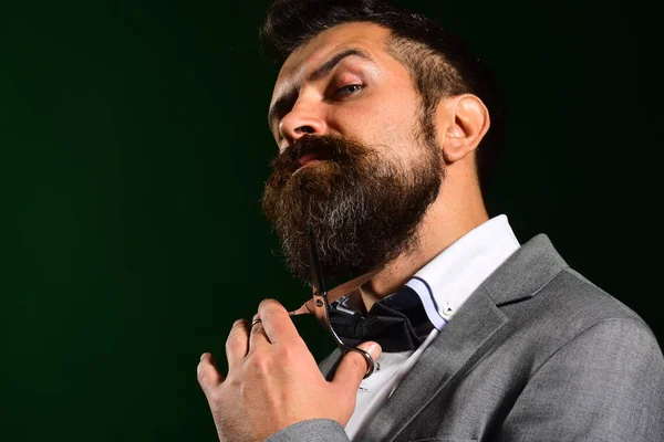 Macho in formal suit cuts beard and moustache.