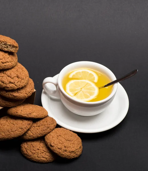 Cookies near tea on dark grey background — Stock Photo, Image