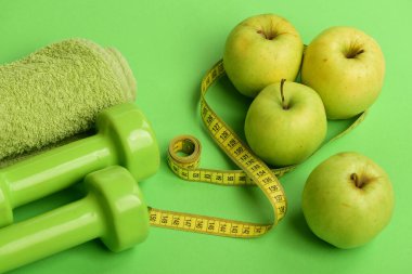 Plastikten yapılmış halterler sulu yeşil elmaların yanında.