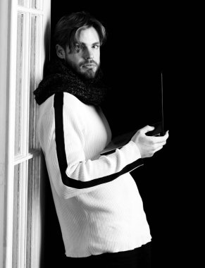 Siyah arka planda dizüstü bilgisayarı olan yakışıklı sakallı adam tahta kapının yanında dizüstü bilgisayar tutuyor, boşluğu kopyalıyor.