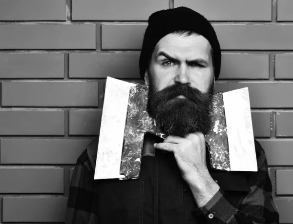 Бородатый рабочий держит лопатки с серьезным лицом — стоковое фото
