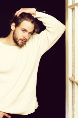 Siyah arka planı olan sakallı yakışıklı adam ahşap kapının yanında.