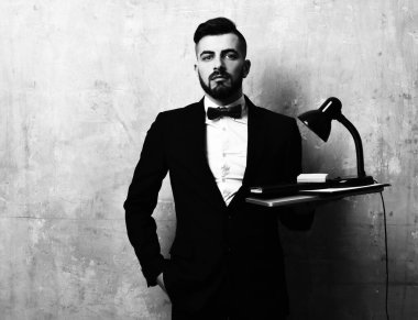 Sakallı ofis çalışanı dizüstü bilgisayar, lamba ve kırtasiye malzemesi tutuyor.