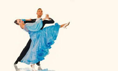 Dans eden balo çifti siyah arka planda yalnız poz verir.