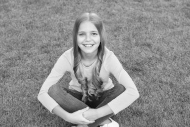 Havalı ve şık. Kıvırcık saçlı çocuk. Kuaföre gittikten sonra küçük bir güzellik. moda ve güzellik. Mutlu çocuklar günü. Bahar tatili Yeşil çimlerin üzerinde kaygısız bir çocuk. Güzel gülüşlü küçük kız